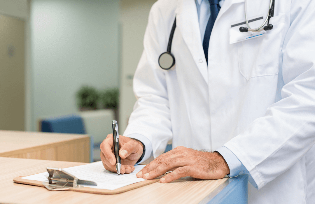 Doctor filling out medical paperwork during an Independent Medical Exam for a workers’ compensation claim