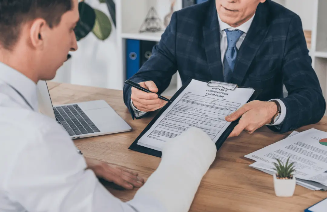 Pennsylvania workers' compensation attorney reviewing a claim with an injured worker wearing an arm cast during a consultation about workers' compensation benefits for two jobs.